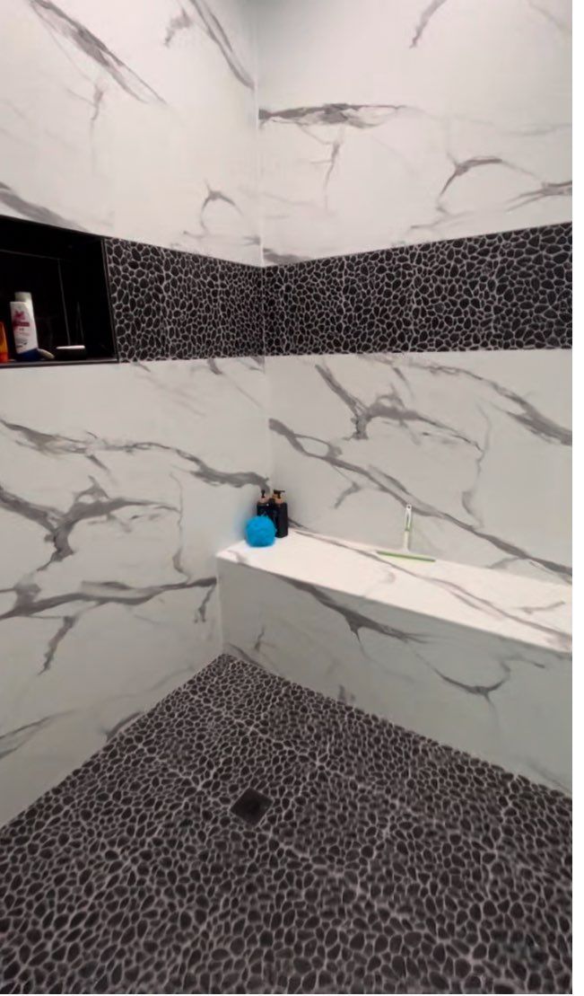 A bathroom with marble tiles and a bathtub.