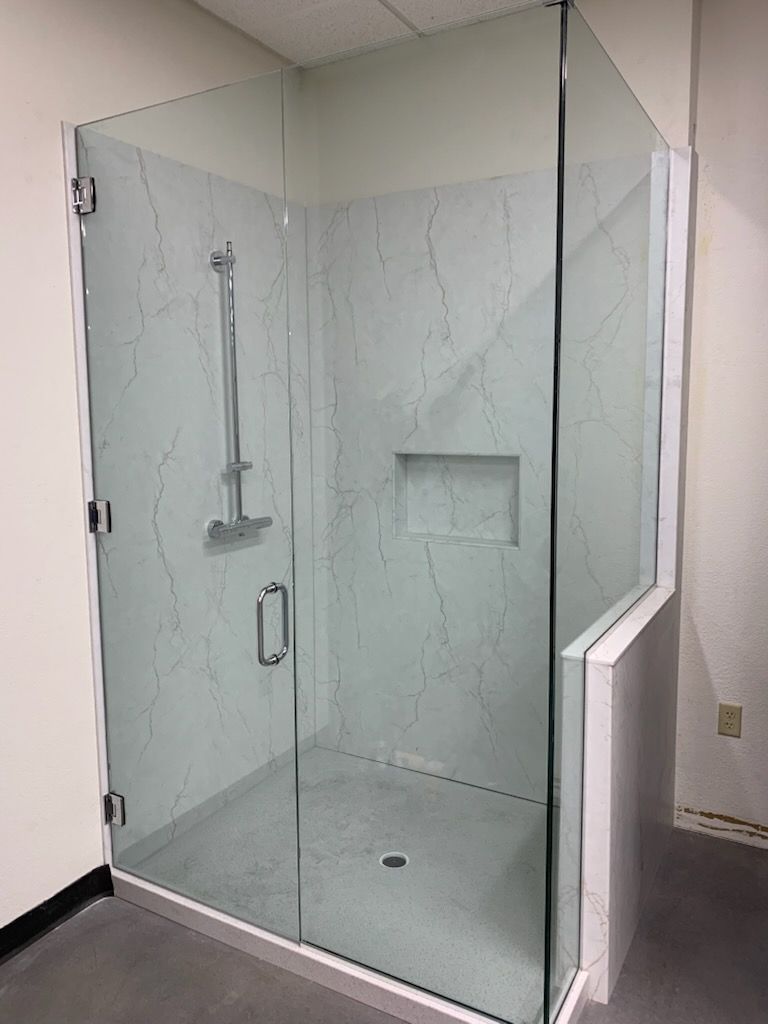 A bathroom with a walk in shower with a glass door.