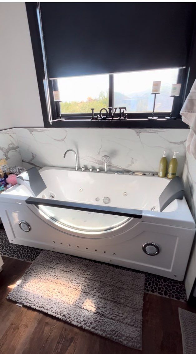 A bathtub in a bathroom next to a window.