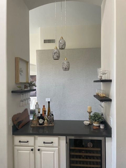 A kitchen with white cabinets and a wine cooler
