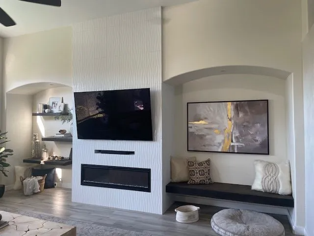 A living room with a fireplace and a flat screen tv on the wall.