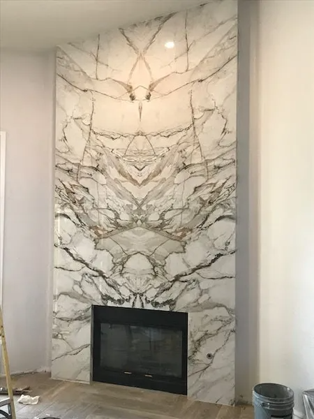 A fireplace with a marble wall surrounding it in a living room.