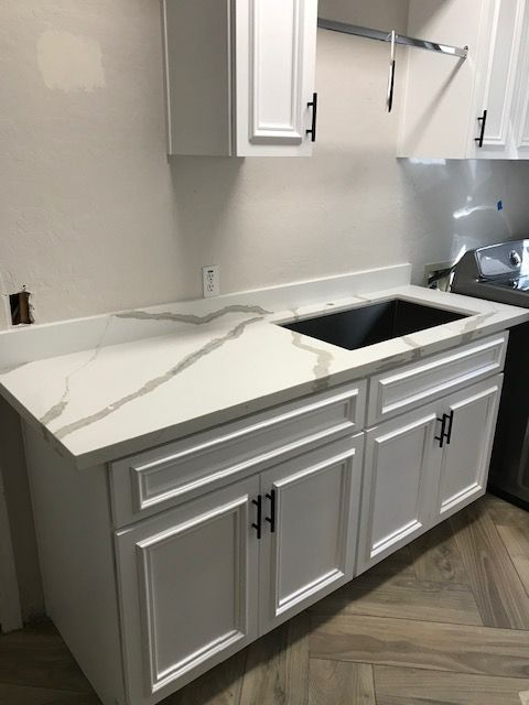 A kitchen with white cabinets and a sink