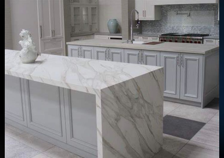 A kitchen with white cabinets and a large marble counter top.