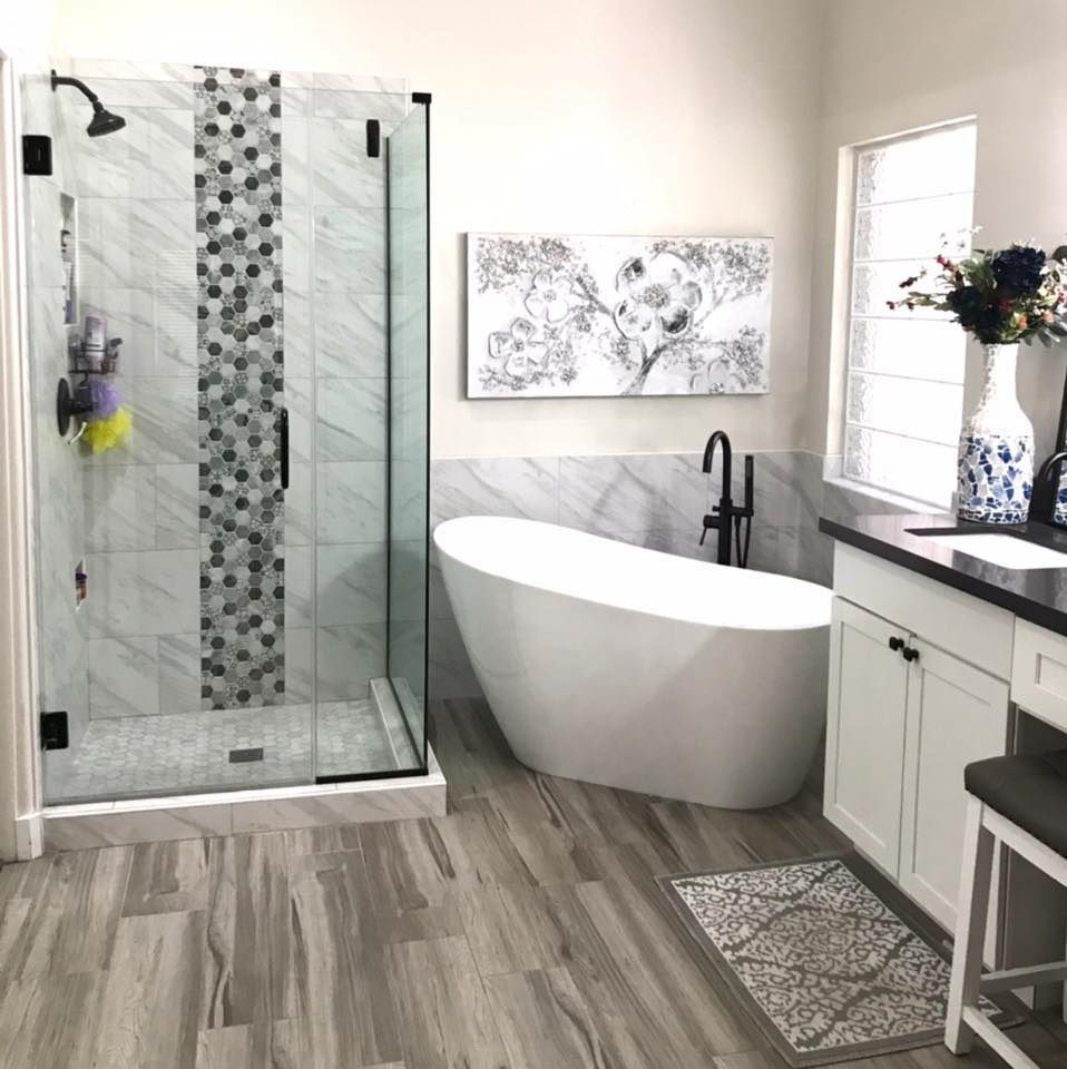 Bathroom with a white freestanding tub, glass shower, and white vanity with dark countertop.