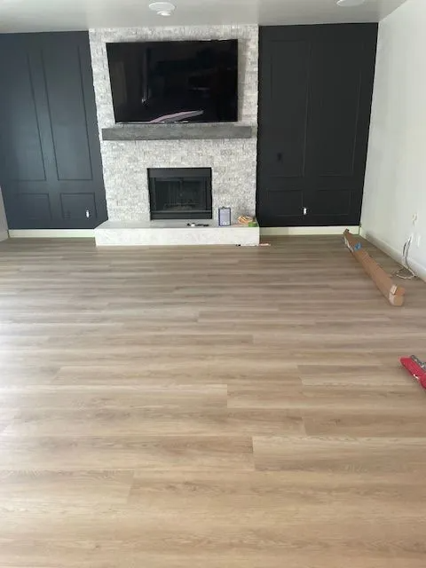 A living room with hardwood floors , a fireplace and a flat screen tv.