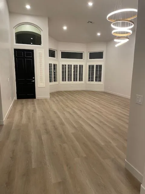 A large empty room with hardwood floors and a black door.