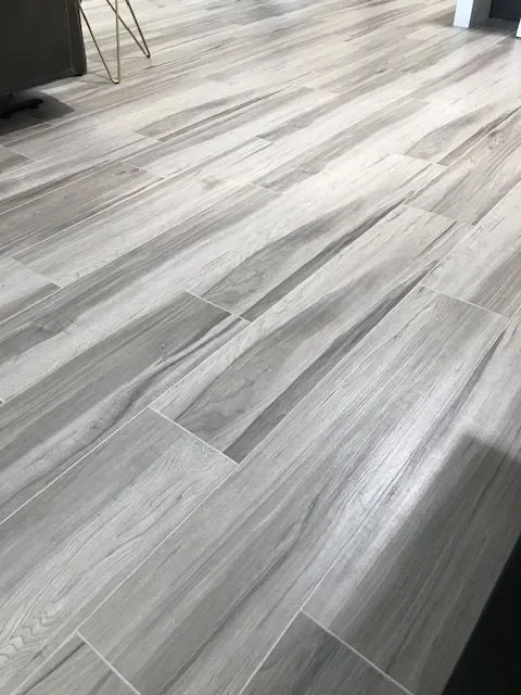 A close up of a gray tile floor that looks like wood.