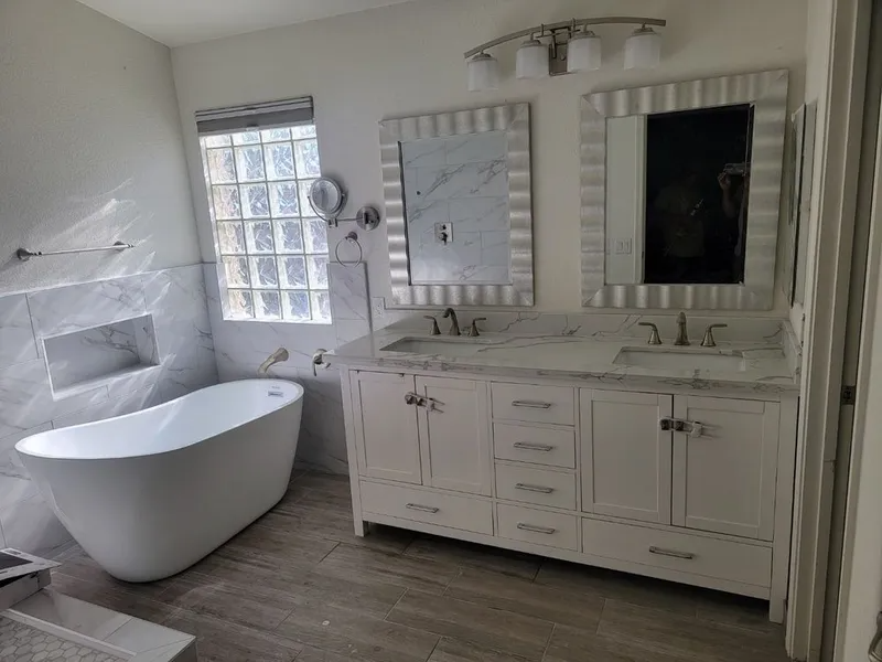 A bathroom with two sinks , a tub , and two mirrors.
