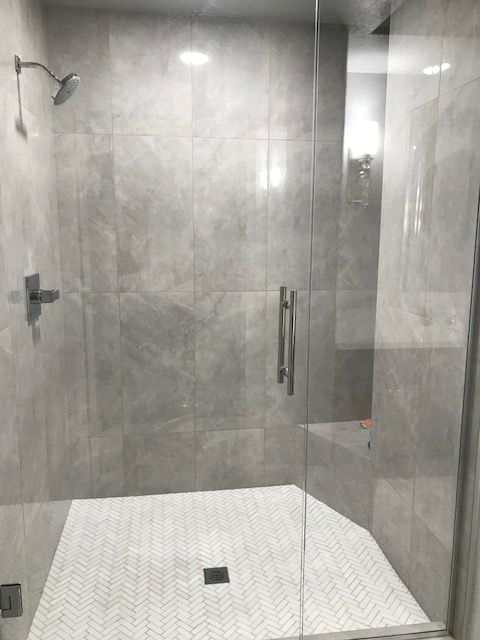 A bathroom with a walk in shower with a glass door.