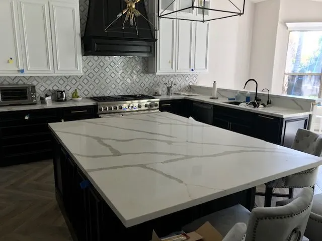 A kitchen with a large white counter top and black cabinets.