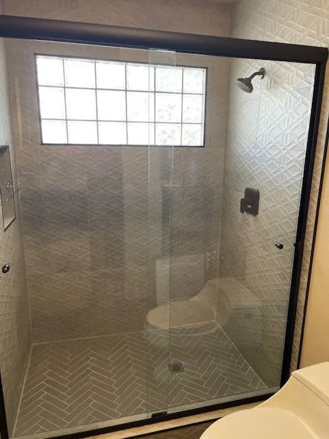 A bathroom with a toilet and a shower with a sliding glass door.