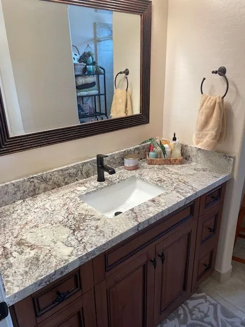A bathroom with a sink , mirror and towel rack.