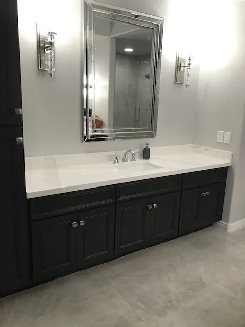 A bathroom with a sink , mirror and cabinets.