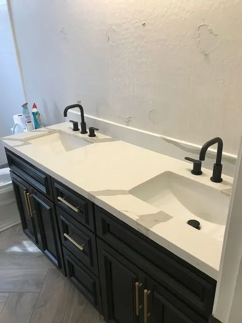 A bathroom with two sinks and black faucets