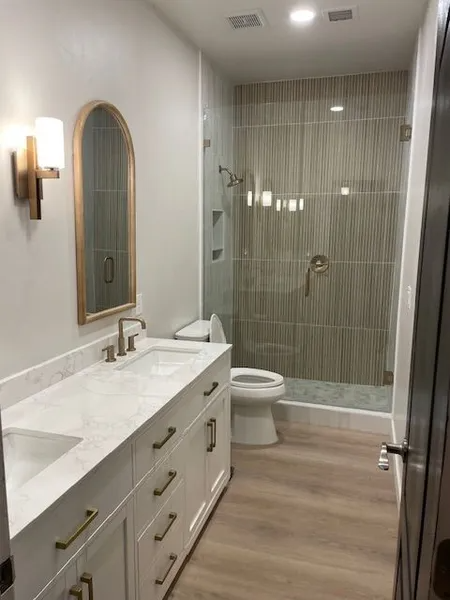 A bathroom with a toilet , sink , mirror and walk in shower.