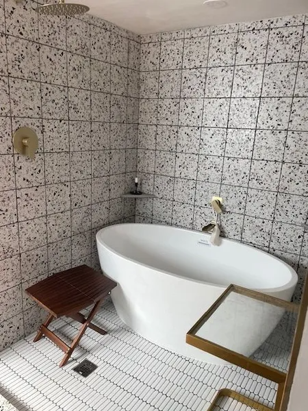 A bathroom with a bathtub and a wooden stool