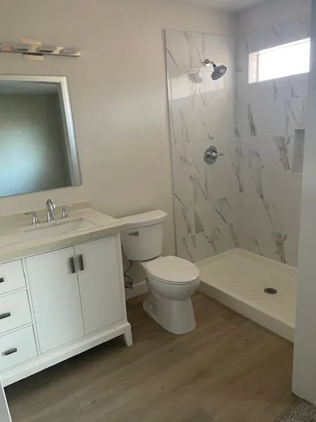 A bathroom with a toilet , sink and shower.