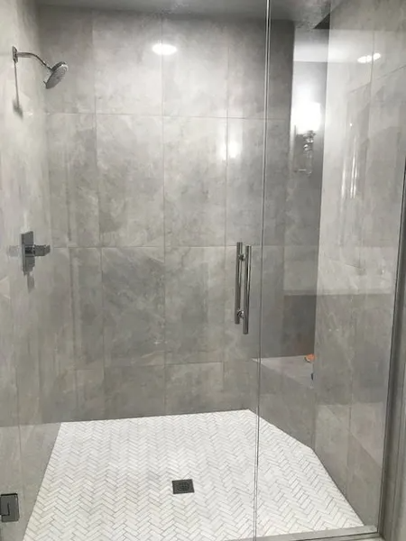 A bathroom with a walk in shower with a glass door.
