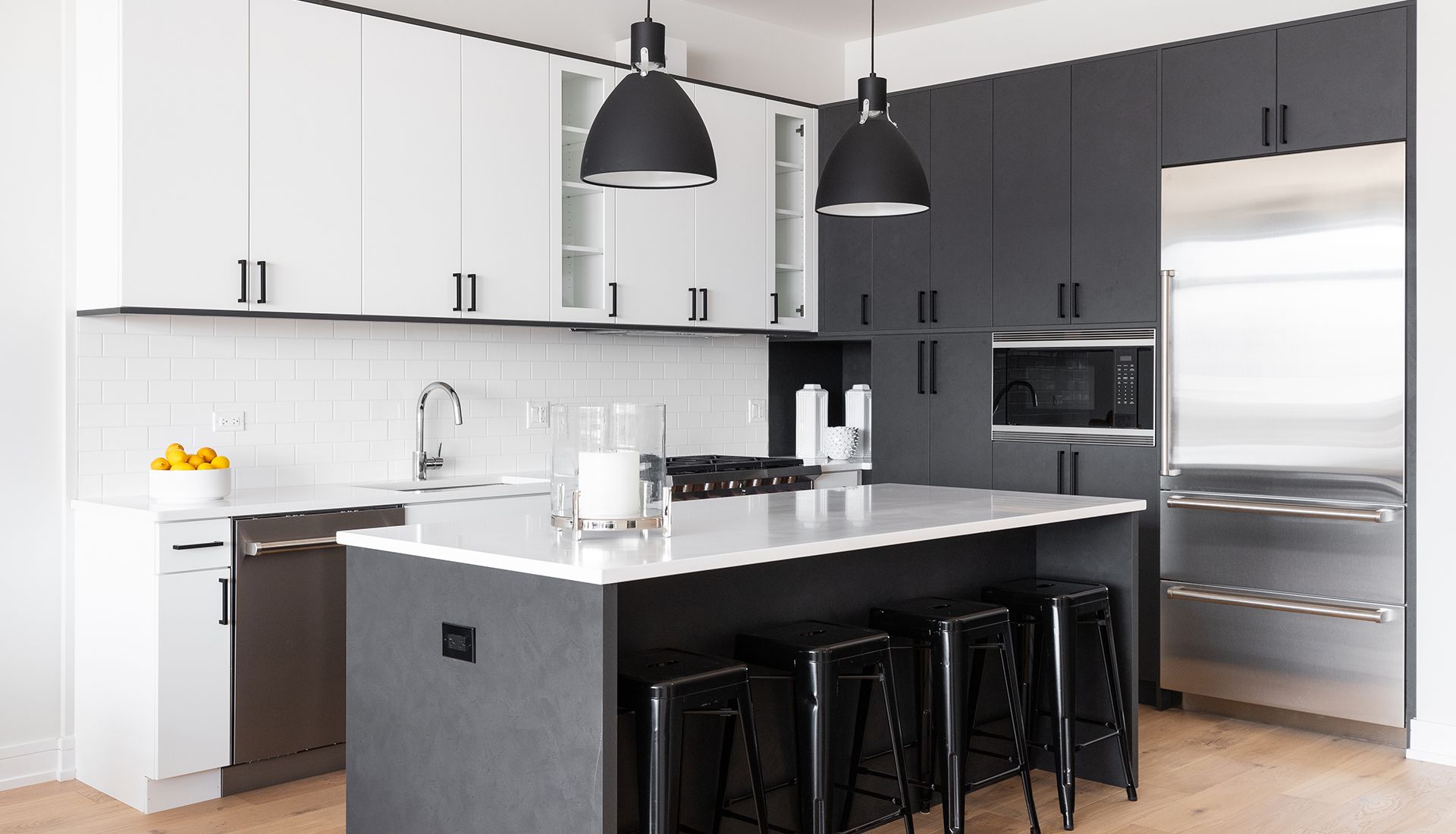 A kitchen with black cabinets and stools and a large island.