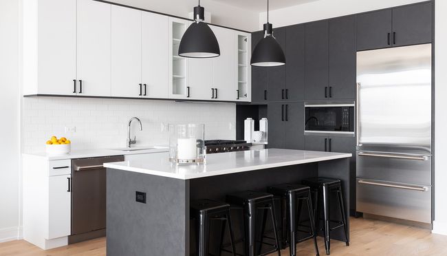 A kitchen with black cabinets and stools and a large island.