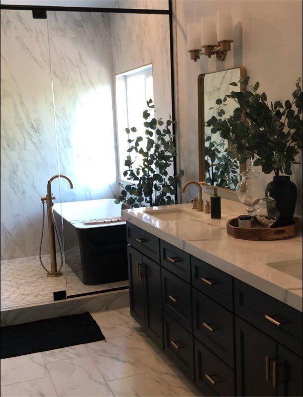 Bathroom with black vanity, marble countertops, and a freestanding black tub.