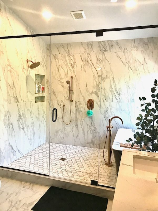 Modern bathroom with marble tile shower and hexagon tile floor. Copper fixtures.