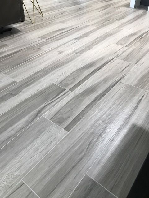A close up of a gray tile floor that looks like wood.