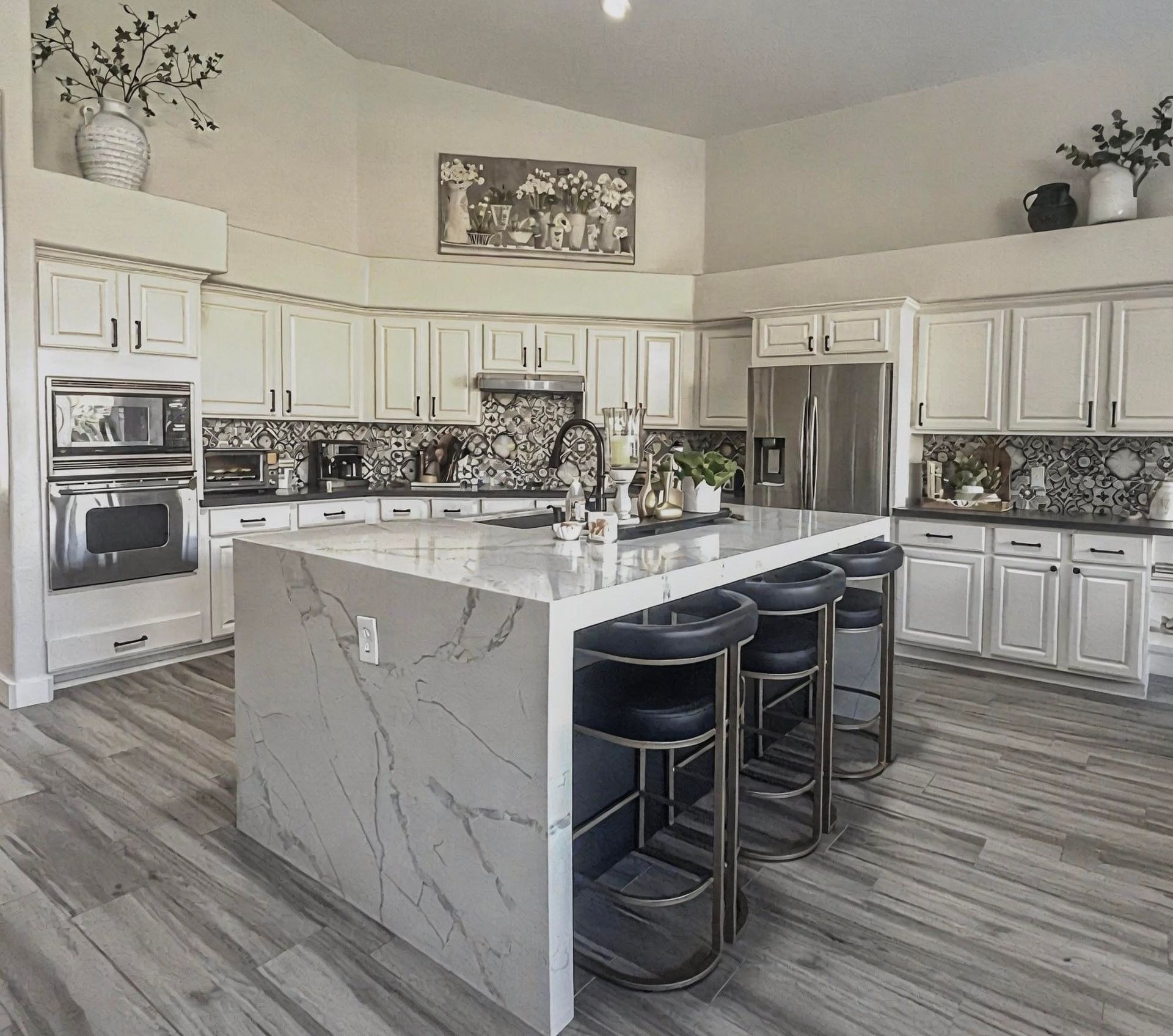 A kitchen with white cabinets , stainless steel appliances and a large island.