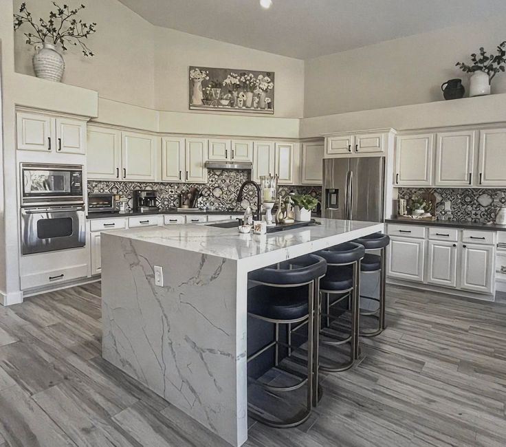A kitchen with white cabinets , stainless steel appliances and a large island.