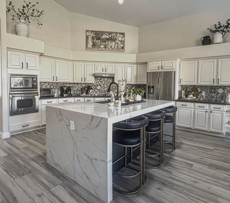 A kitchen with white cabinets , stainless steel appliances and a large island.