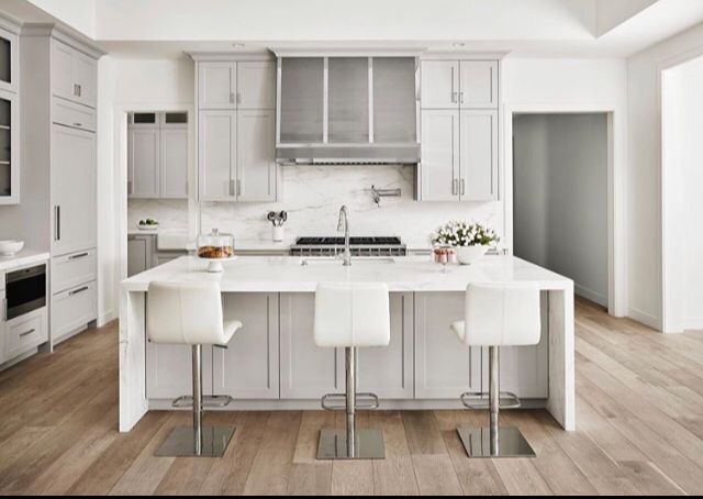 A kitchen with white cabinets and stools and a large island