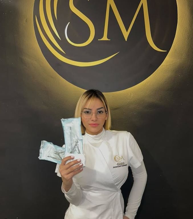 Una donna con una camicia bianca tiene in mano un pacco davanti a un logo di piccole dimensioni