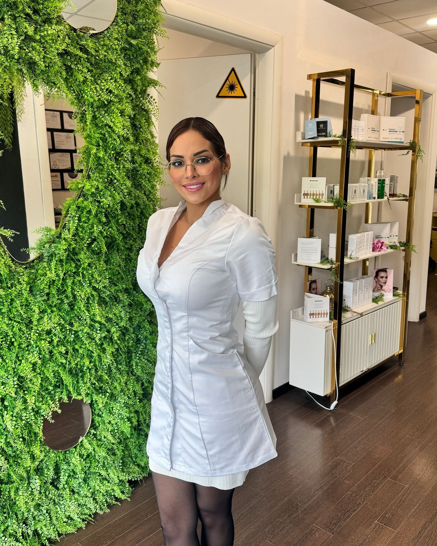 Una donna vestita di bianco è in piedi davanti a un muro verde.