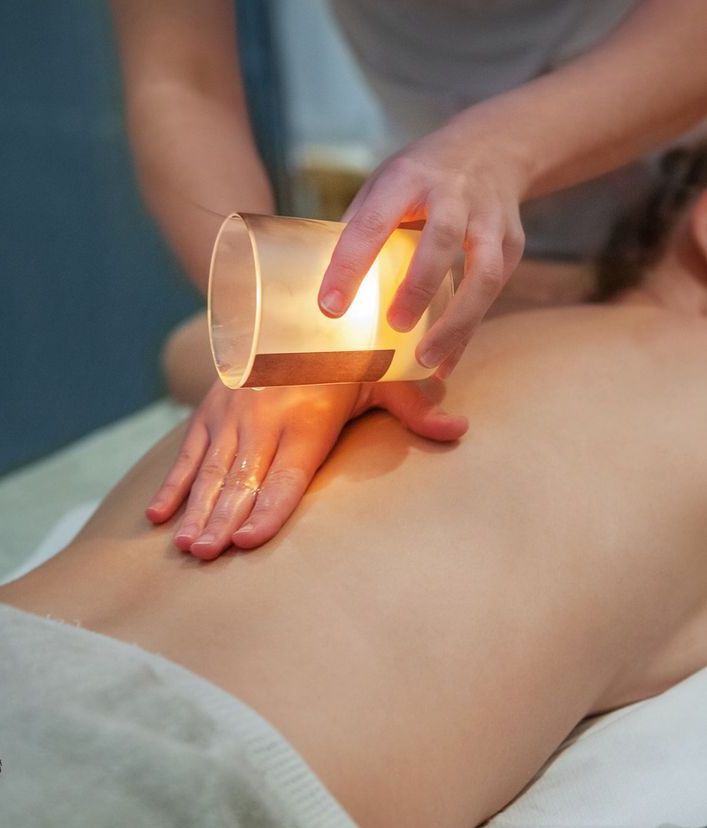 Una donna riceve un massaggio con una candela sulla schiena.