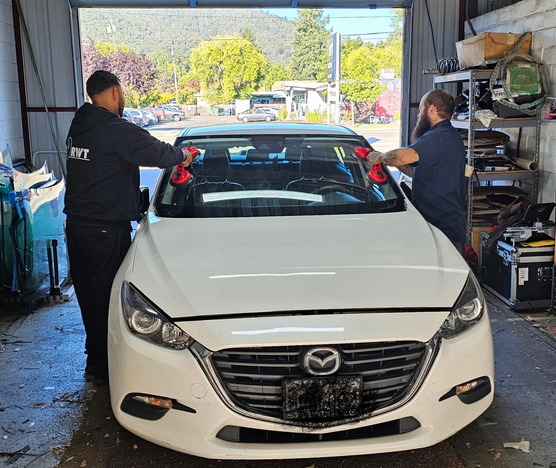 A car windshield is being replaced in a garage.