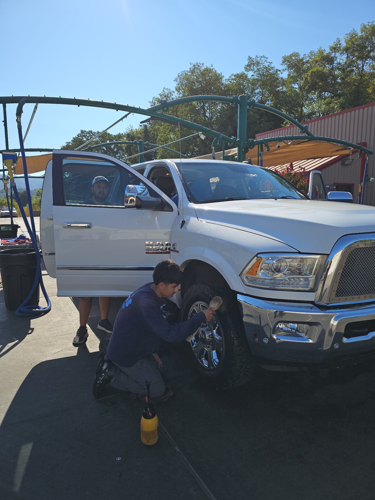 A person wearing pink gloves is washing a car with a sponge.