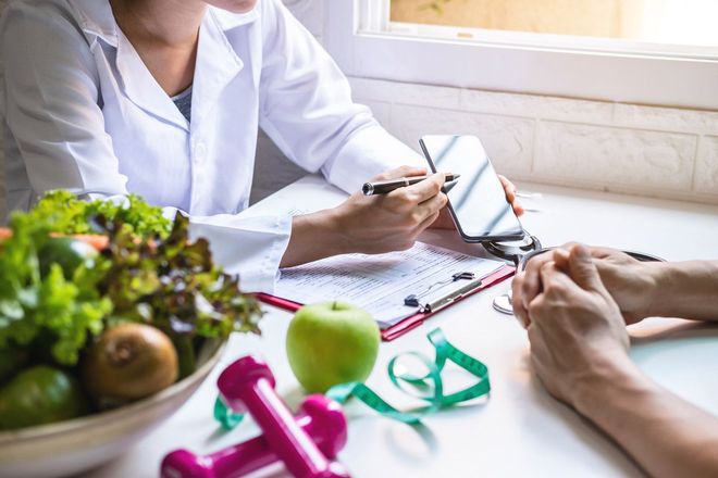 A woman is sitting at a table talking to a nutritionist.