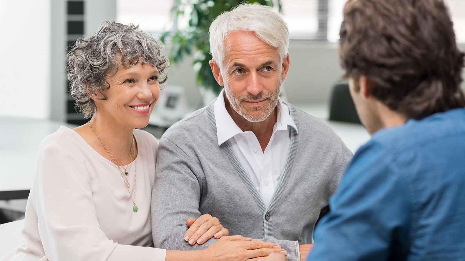 Older couple consults with a younger man at a table, likely a financial advisor.