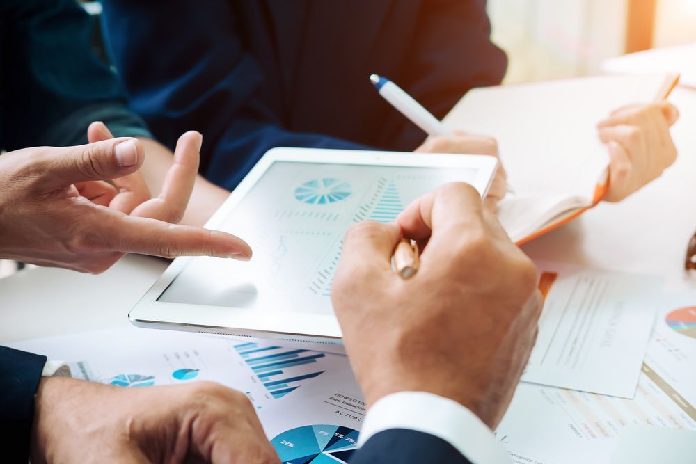 Hands Pointing at Charts on a Tablet, Financial Documents on a Table — Adamson Town Planning in Noosaville, QLD