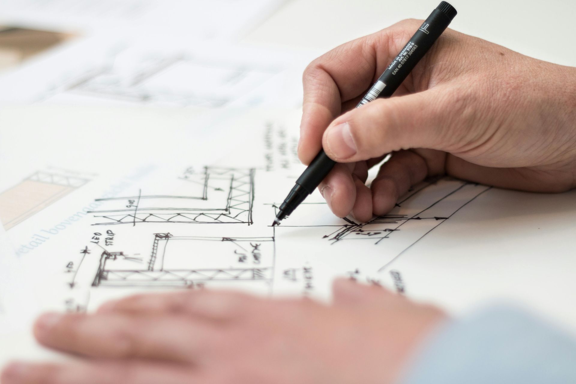 Two people working on architectural blueprints, using tools on a white table. — Adamson Town Planning in Noosaville, QLD