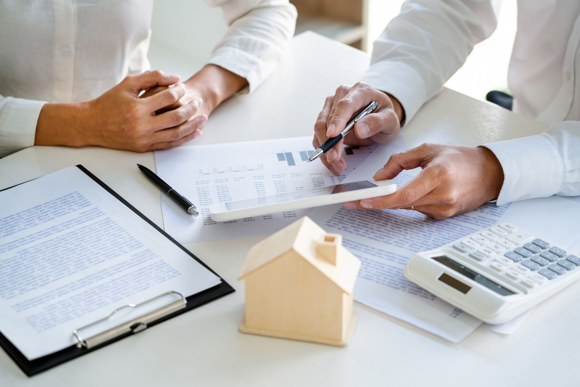 Two People Reviewing Documents, Calculator, and House Model on a Desk — Adamson Town Planning in Noosaville, QLD