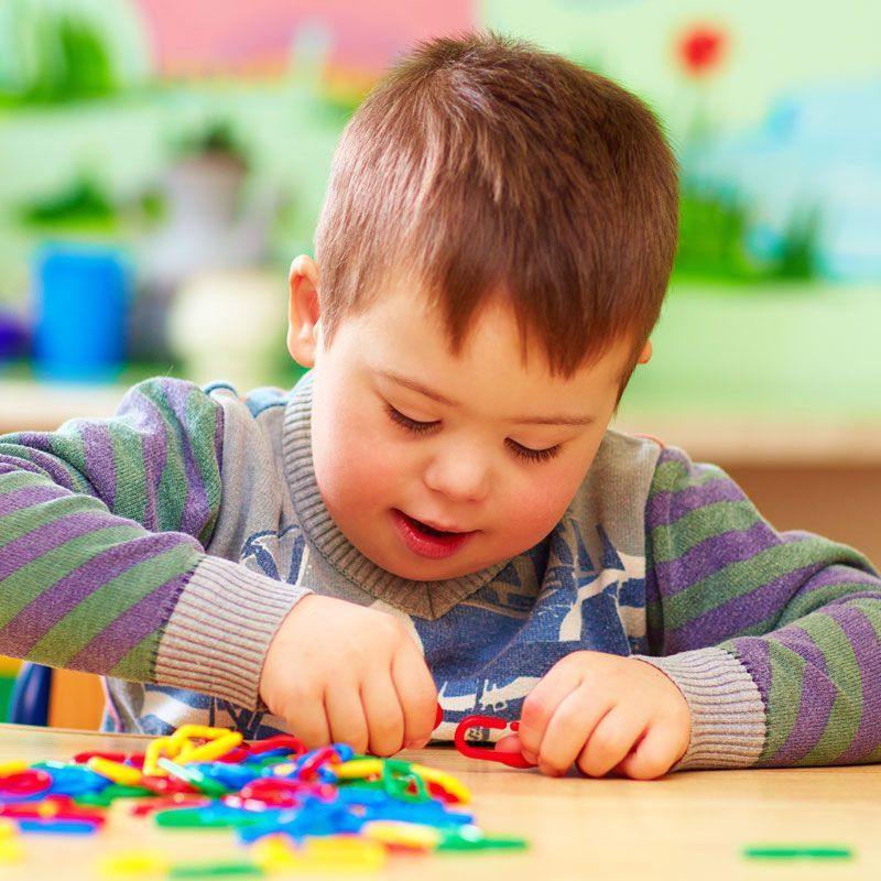 A young boy is sitting at a table playing with colorful toys.