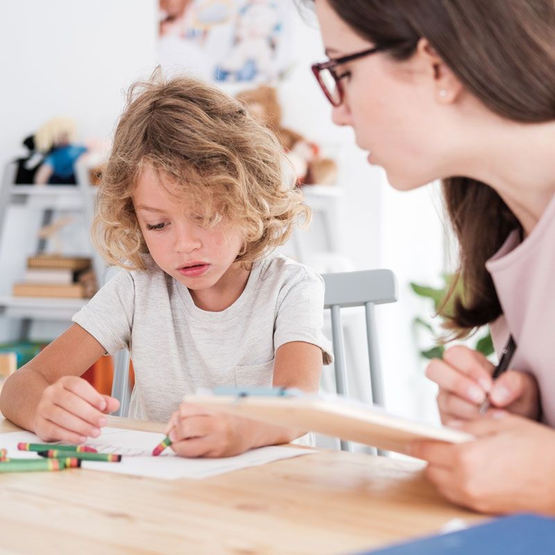 A woman is helping a young boy with his homework.