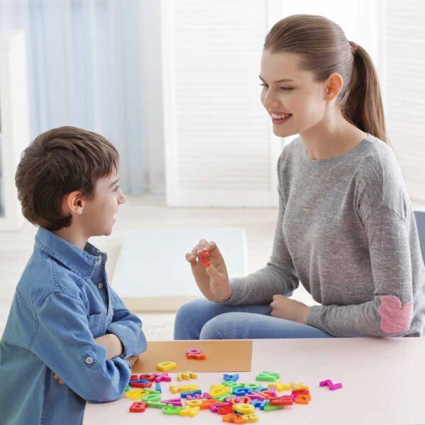 A Woman Is Sitting At A Table Talking To A Young Boy