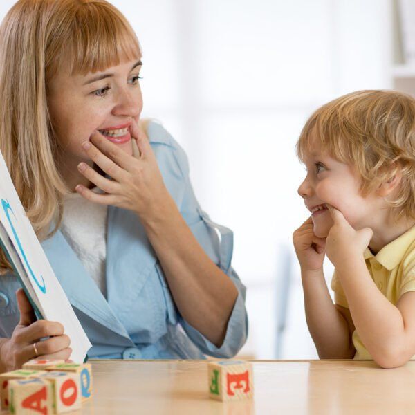 A Woman Is Sitting At A Table With A Child Playing With Blocks