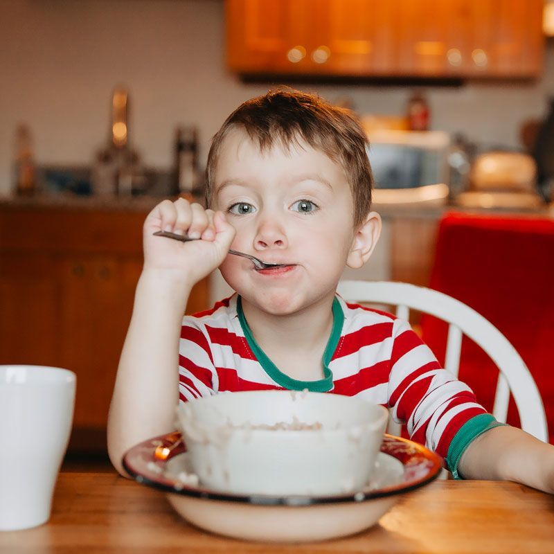 A young boy is eating from a bowl with a spoon