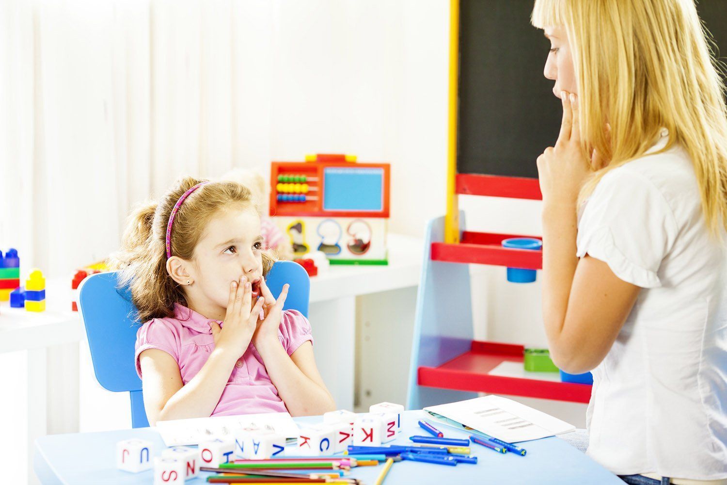 A Woman Is Teaching A Little Girl How To Draw A House