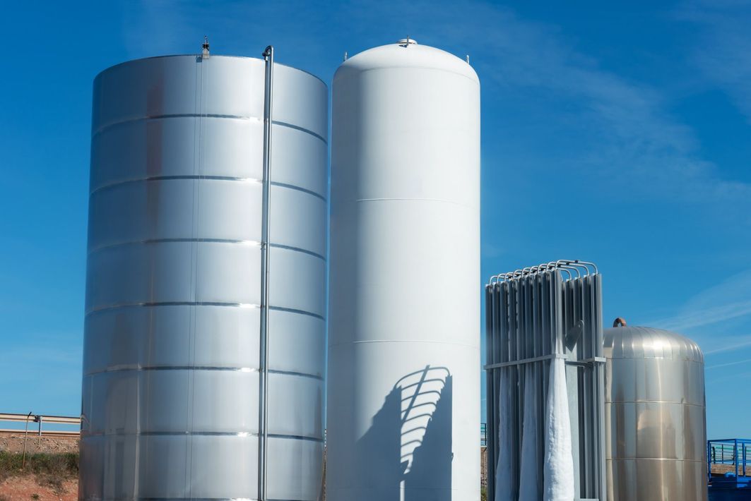 A group of stainless steel tanks sitting next to each other on a sunny day