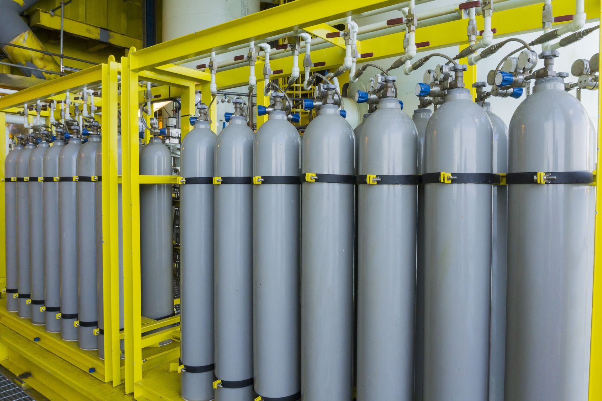 A row of gas cylinders are lined up in a warehouse